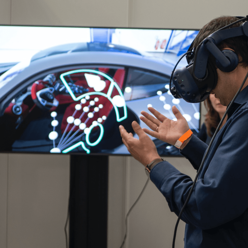 A man wearing a VR headset looking at the interior of a car